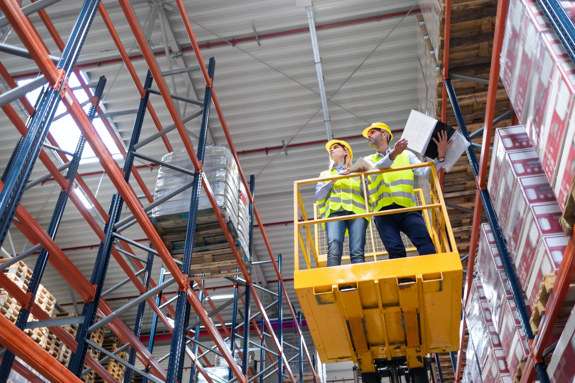 Warehouse workers on the height using lift work platform to check inventory